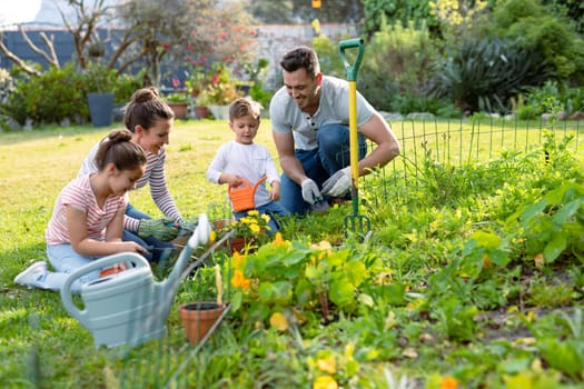 Happy caucasian family gardening and watering plants together. family time, having fun together at home and garden.