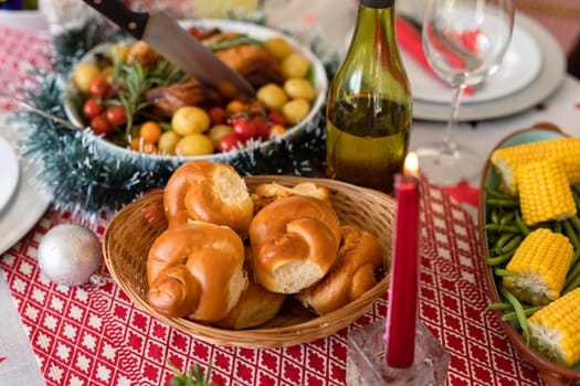 Fresh rolls, dishes, candles and decorations on christmas table. christmas, festivity and tradition at home.