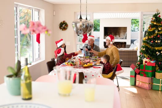 Caucasian multi generation family wearing santa hats having christmas meal. family christmas time and festivity together at home.