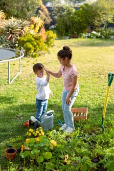 Happy caucasian sister and brother gardening together, giving high five. family time, having fun together at home and garden.