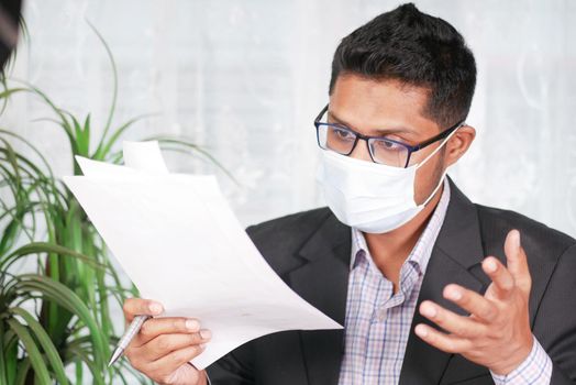 young man with face mask reading something on a paper .