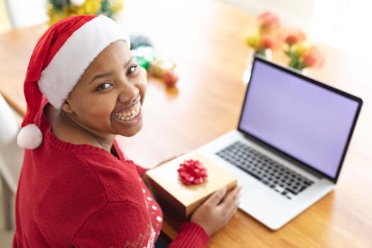 Happy african american plus size woman making christmas video call on laptop with copy space. christmas, festivity and communication technology.