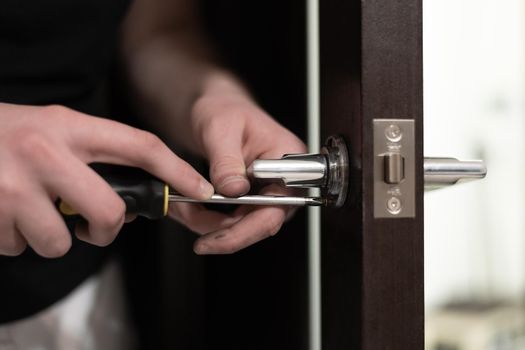 A man installs a handle on a wooden door