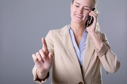 Caucasian businesswoman talking on smartphone using virtual interface, isolated on grey background. business, technology, communication and growth concept.