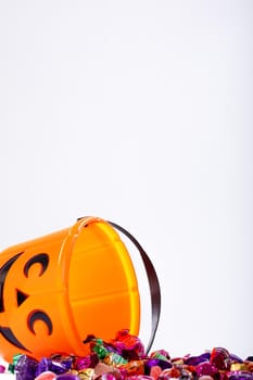 Composition of halloween bucket with trick or treat sweets on white background. halloween tradition and celebration concept.