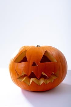 Composition of scary halloween carved orange pumpkin on white background. halloween tradition and celebration concept.