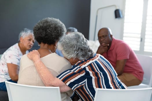 Back view of caucasian senior woman embracing african american female friend and supporting her. senior health, support and lifestyle.