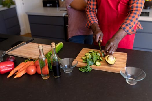 Midsection of african american senior couple cooking together in kitchen. retirement lifestyle, leisure and spending time at home.