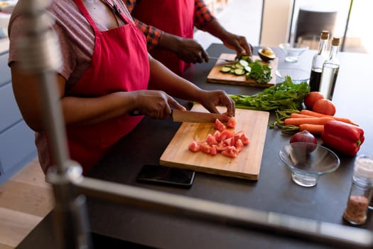 Midsection of african american senior couple cooking together in kitchen. retirement lifestyle, leisure and spending time at home.
