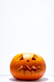 Composition of scary halloween carved orange pumpkin on white background. halloween tradition and celebration concept.