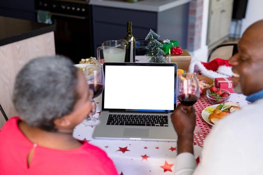 African american senior couple having video call on laptop with copy space at christmas time. retirement lifestyle, christmas festivities and communication technology.
