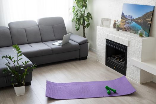 Training at home concept, interior, decorative sport in the room with gym fitness exercise purple mat, dumbbell.