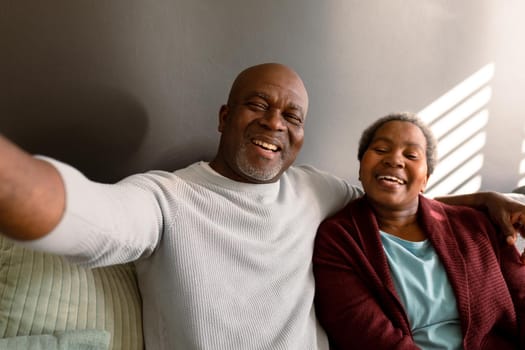 Happy african american senior couple taking selfie at home. retirement lifestyle, communication technology and spending time at home.