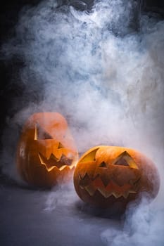 Composition of halloween carved pumpkins and cloud of smoke with copy space on black background. halloween tradition and celebration concept.