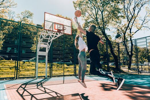 Young man with prosthetic leg playing basketball with his friend at a court.