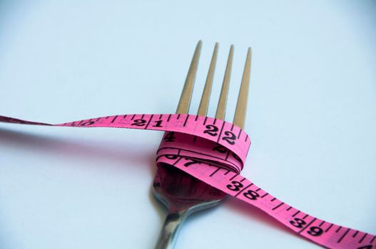 Fork tied with measuring tape. Weight loss and fitness concept