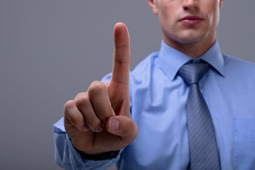 Midsection of caucasian businessman touching virtual interface, isolated on grey background. business technology, communication and growth concept.