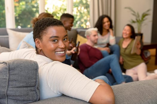 Happy african american woman having fun with diverse group of female and male friends at home. socialising with friends at home.