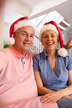 Happy caucasian senior couple wearing santa hat, having video call at christmas time. christmas, festivity and communication technology.