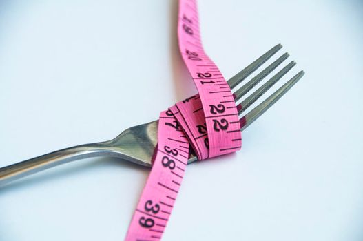 Fork tied with measuring tape. Weight loss and fitness concept