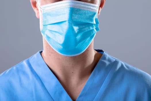 Caucasian male doctor wearing face mask, isolated on grey background. medical and healthcare technology concept during covid 19 coronavirus pandemic concept digitally generated composite image.