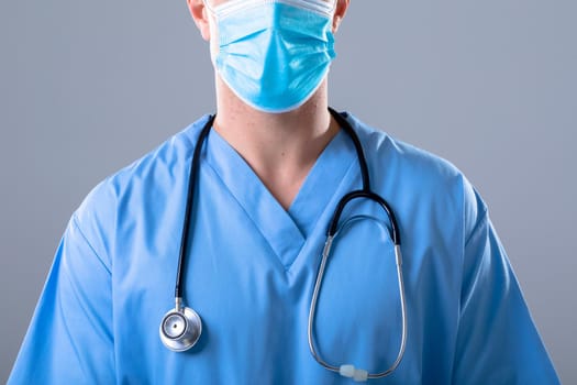 Caucasian male doctor wearing face mask, isolated on grey background. medical and healthcare technology concept during covid 19 coronavirus pandemic concept digitally generated composite image.