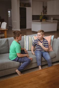 Two caucasian boys communicating using sign language while sitting on the couch at home. sign language learning concept