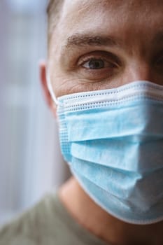 Close up view of caucasian man wearing face mask at home. coronavirus covid-19 pandemic concept