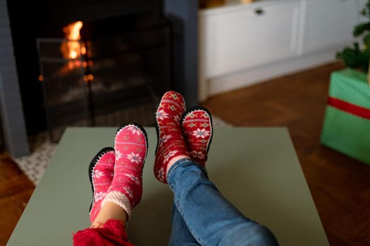 Feet of caucasian couple wearing christmas socks at christmas time. family christmas time and festivity together at home.