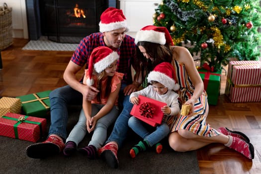 Happy caucasian family wearing santa hat, holding presents at christmas time. family christmas time and festivity together at home.