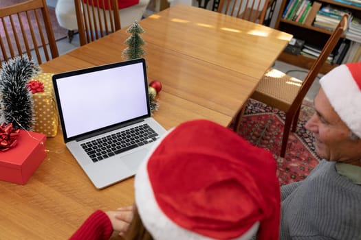 Caucasian woman and senior man having video call on laptop with copy space at christmas time. christmas, festivity and communication technology at home.