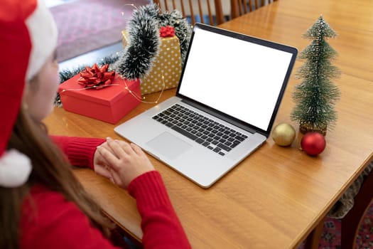 Caucasian woman wearing santa hat having video call on laptop with copy space at christmas time. christmas, festivity and communication technology at home.