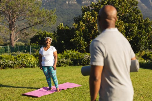 Portrait of smiling senior african american couple with yoga mat in countryside retreat. retirement and active senior lifestyle concept.