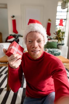 Albino african american man wearing santa hat making video call with christmas decorations. christmas, festivity and communication technology festivity and communication technology.