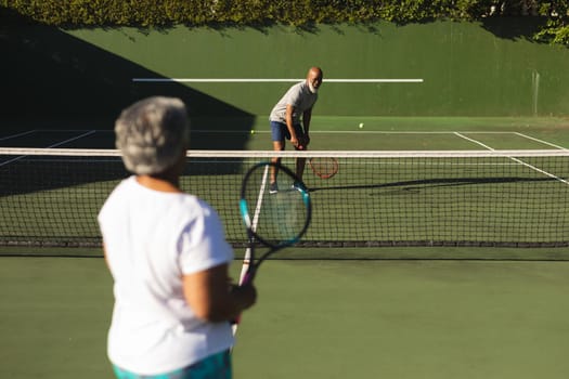 Senior african american couple playing tennis on tennis court. retirement and active senior lifestyle concept.