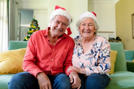 Happy caucasian senior couple in santa hats having video call at christmas time. christmas, festivity and communication technology.