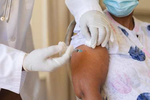 Senior african american woman in face mask receiving vaccination. retirement and senior lifestyle during covid 19 pandemic concept.