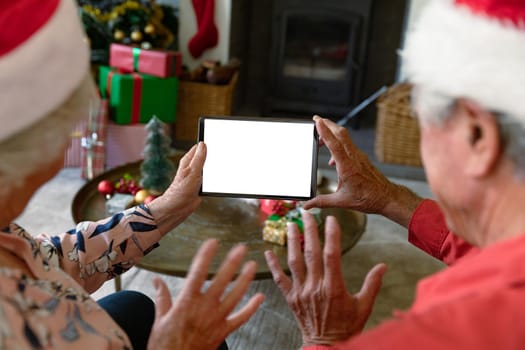 Caucasian senior couple wearing santa hats using tablet with copy space at christmas time. christmas, festivity and communication technology.