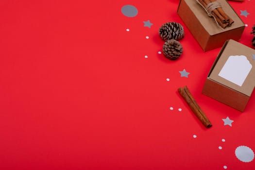 Composition of christmas decorations with pine cones, cinnamon and copy space on red background. christmas, tradition and celebration concept.