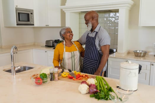 Senior african american couple cooking together in kitchen smiling. retreat, retirement and happy senior lifestyle concept.