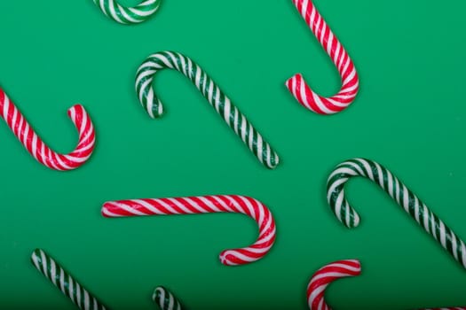 Composition of multiple green and red candy canes on green background. christmas, tradition and celebration concept.