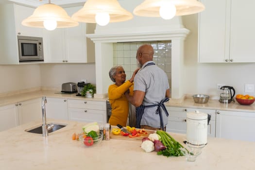 Senior african american couple cooking together in kitchen smiling. retreat, retirement and happy senior lifestyle concept.