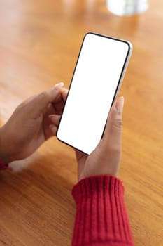 Hands of african american woman holding smartphone with copy space at christmas time. christmas, festivity and communication technology.