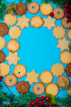 Composition of christmas cookies with tree branches and copy space on blue background. christmas, tradition and celebration concept.