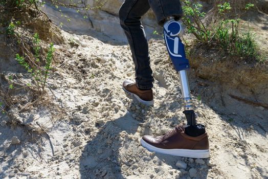 a man on a prosthetic leg travels the mountains. Dressed in black jeans.