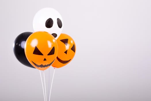 Orange, black and white halloween balloons over white background. halloween tradition and celebration concept digitally generated image.