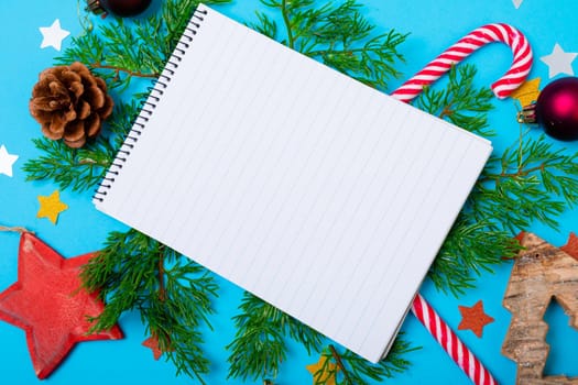 Composition of notebook with copy space and christmas decorations on blue background. christmas, tradition and celebration concept.