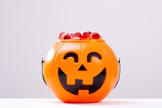 Composition of halloween bucket with trick or treat sweets on white background. halloween tradition and celebration concept.