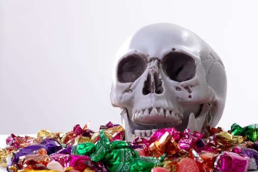 Composition of halloween laughing skull with trick or treat sweets on white background. halloween tradition and celebration concept.