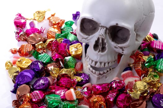 Composition of halloween laughing skull with trick or treat sweets on white background. halloween tradition and celebration concept.
